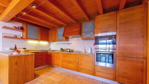 A kitchen with wooden cabinets, a central island, and stainless steel appliances. - Lugano Panoramica (Lugano)