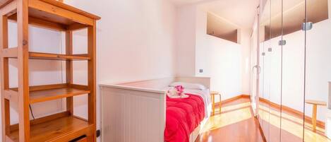 A bedroom with a bed, a wooden cabinet, and a wardrobe.