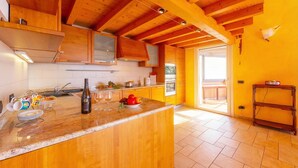 A kitchen with wooden beams, a marble countertop, and a view to the outside. - Lugano Panoramica (Lugano)