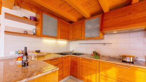 A kitchen with wooden cabinets, a granite countertop, a sink, and a stove. - Lugano Panoramica (Lugano)