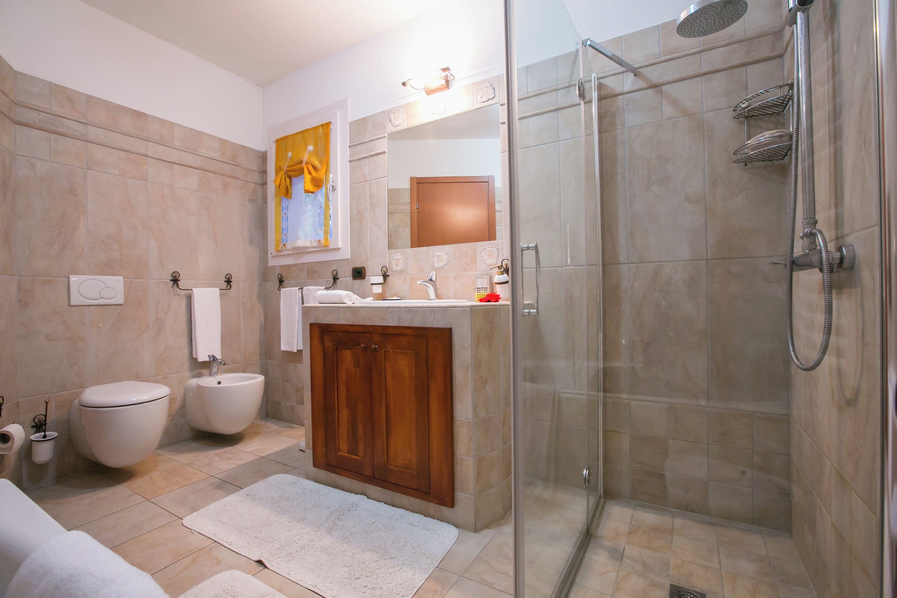 Une salle de bain avec une douche à parois de verre, des toilettes, un bidet et un lavabo avec un meuble en bois.