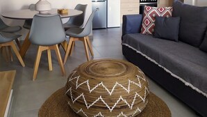 A modern living room with a dark grey sofa, a round woven rug, and a dining area with a white table and grey chairs. - Europa,2br,2bth Villa With Private Pool And Stunning Sea Views (Skiathos)