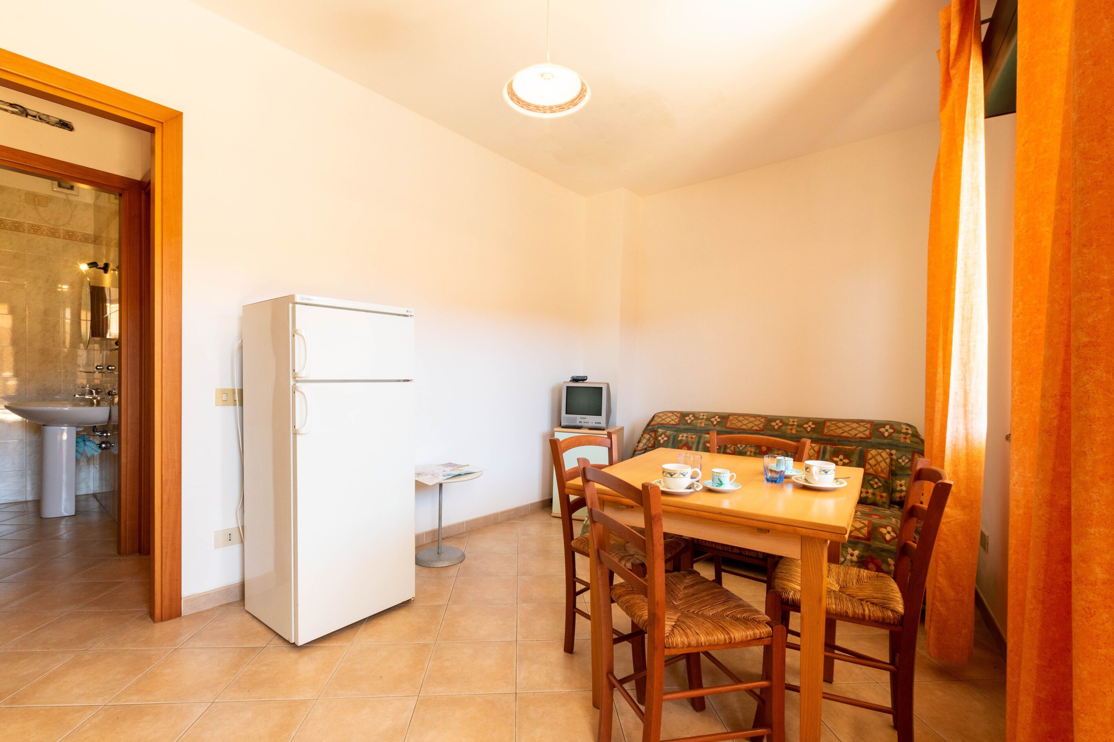 A compact living space with a kitchenette, a dining area with a table and chairs, and a sofa.