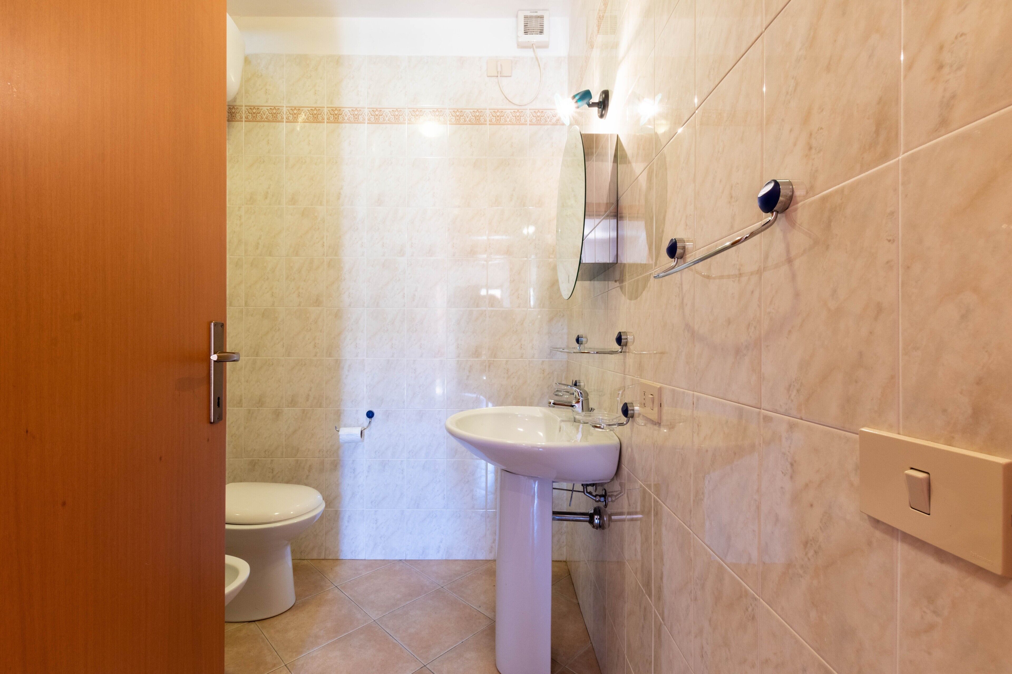 A bathroom with a toilet, sink, and mirror.