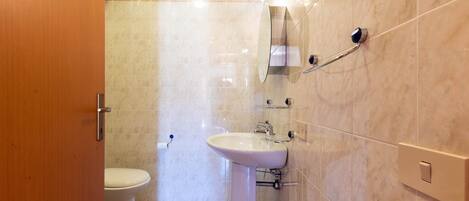 A bathroom with a toilet, sink, and mirror.