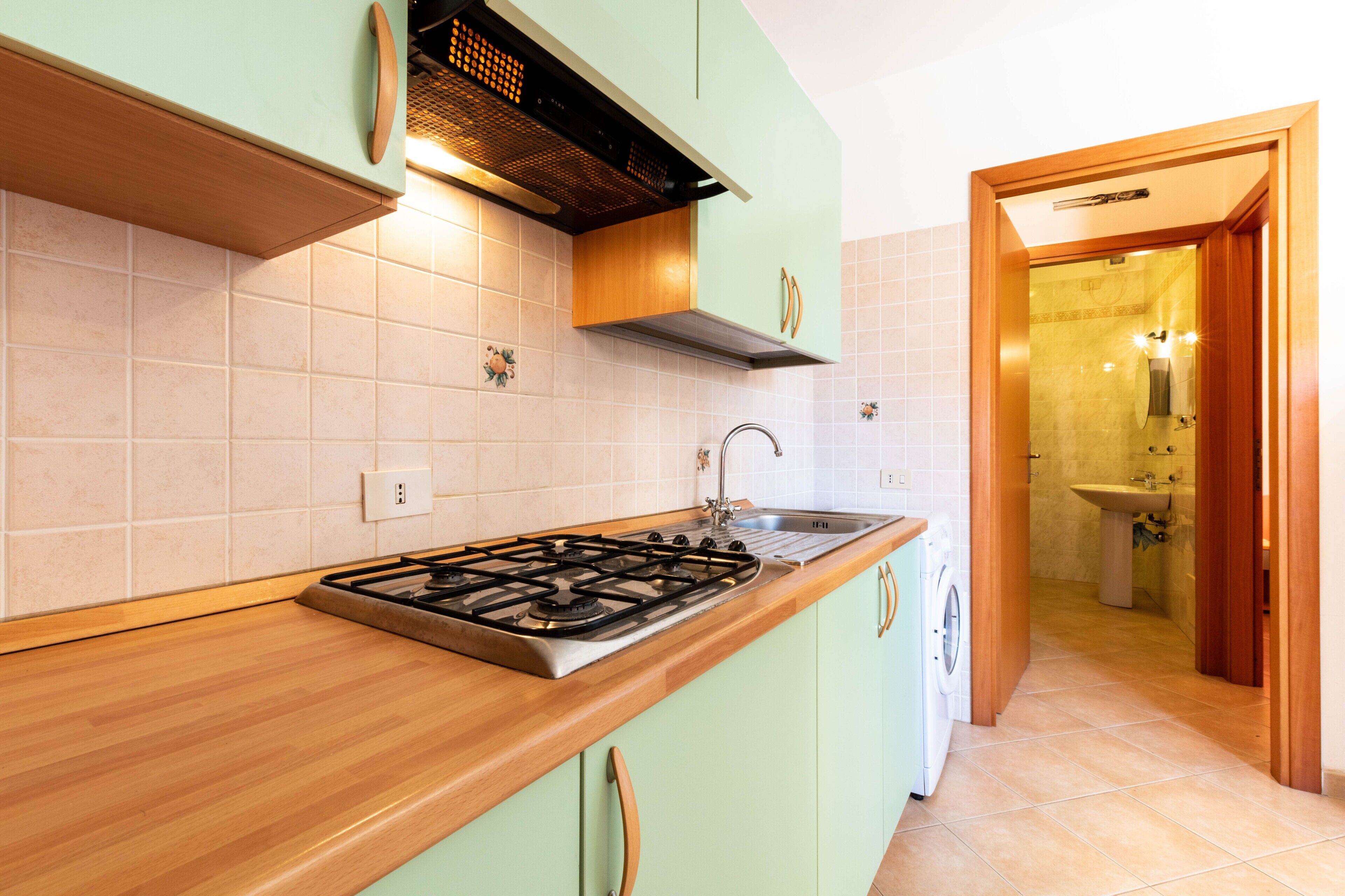 A kitchen with a gas stove, sink, and wooden countertop.