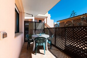 Un balcon avec une table et des chaises, une fenêtre et une clôture décorative.