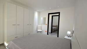 A bedroom with a large bed, a wardrobe, a chair, a bedside table with a lamp, and a mirror. - Villa "White" with Private Pool, Terrace & Wi-Fi (Alcamo)