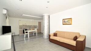 A modern living room with a sofa, a dining area, and a kitchen in the background. - Villa "White" with Private Pool, Terrace & Wi-Fi (Alcamo)
