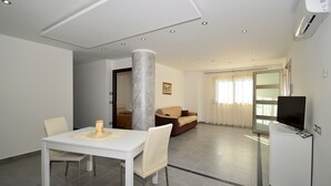 A modern hotel room with a dining area, a sofa, a television, and a large pillar. - Villa "White" with Private Pool, Terrace & Wi-Fi (Alcamo)