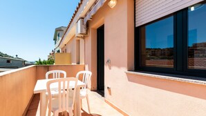 A balcony with a table and chairs, a window, and a door. - City apartment with balcony – Apartment Cavour Codice F (Villasimius)