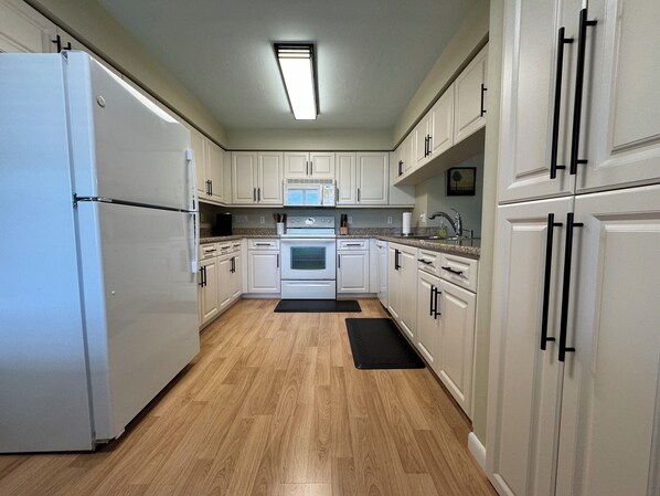 Enjoy cooking in this well-equipped kitchen with a stainless steel refrigerator, oven, and microwave.