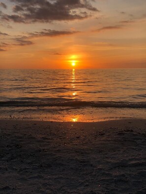 Enjoy a serene beach scene with the sun reflecting off the calm waters.