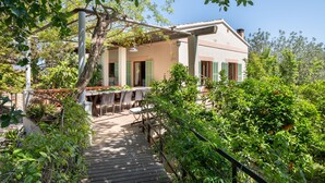 A house with a wooden deck, outdoor seating, and lush greenery. - Holiday Home "Sa Teulera de Sencelles" with Pool & Wi-Fi (Sencelles)
