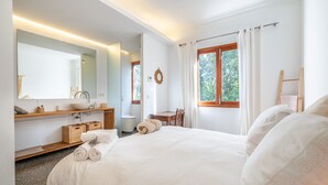 A hotel room with a bed, a bathroom with a mirror, a desk, and a window with curtains. - Holiday Home "Sa Teulera de Sencelles" with Pool & Wi-Fi (Sencelles)