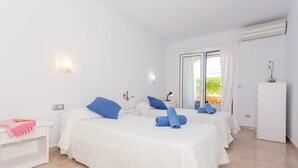 Habitación de hotel con dos camas, un armario blanco, una mesita de noche, un escritorio y una ventana con cortinas.