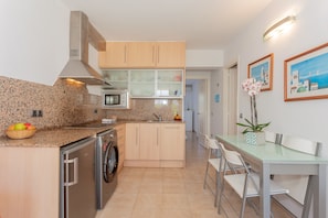 A modern kitchen with granite countertops, stainless steel appliances, and a dining area with a glass table and chairs.