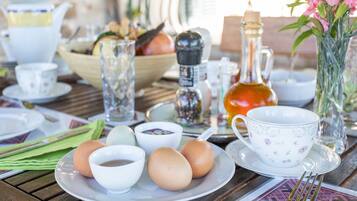 Desayuno con huevos, tazas y una tetera sobre una mesa de madera.
