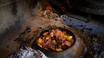 A rustic stone oven with a bowl of roasted meat and potatoes inside.