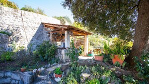 A rustic outdoor area with a stone wall, wooden pergola, and potted plants. - Country House Bakicevo (Konavle)