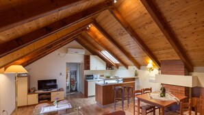 A cozy attic room with a dining area, kitchen, and a TV. - Country House Bakicevo (Konavle)