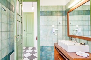 A bathroom with a white sink, a mirror, and green tiles. - Stylish Art Deco Apartment Close To The Beach (Platanias)