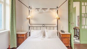 A neatly arranged bedroom with a four-poster bed, two bedside lamps, and a green door in the background. - Stylish Art Deco Apartment Close To The Beach (Platanias)