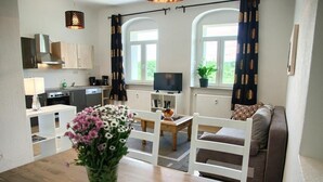 Een ruimtelijke woonruimte met keuken, eethoek en zithoek.