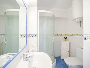 A modern bathroom with a glass shower enclosure, a white sink with a mirror, and a toilet.