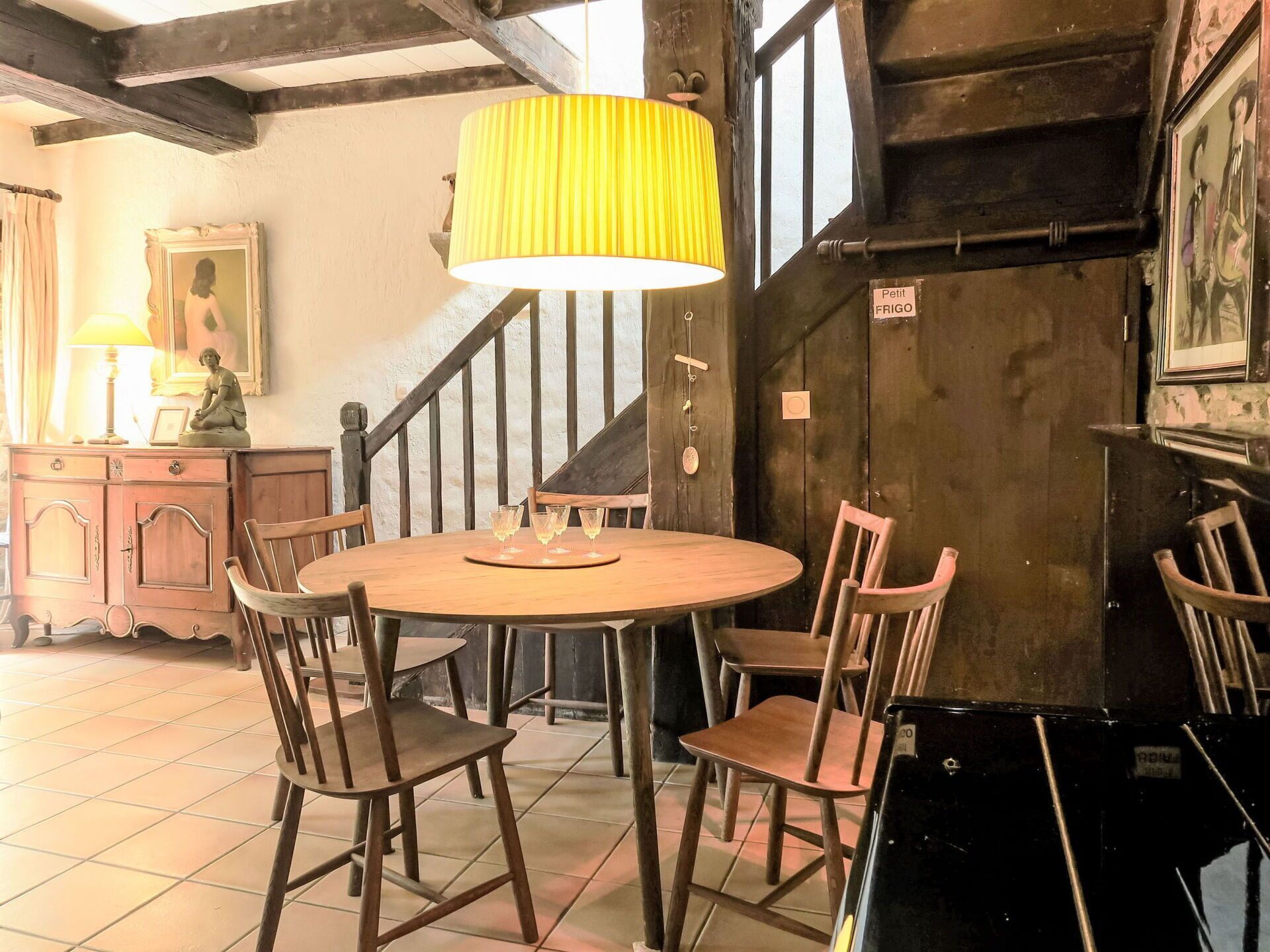 Ein rustikaler Essbereich mit Holztisch und -stühlen, einer gelben Lampe und einer Treppe im Hintergrund.