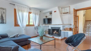 A living room with a sofa, a glass coffee table, a fireplace, and a television. - Beautiful Country House "Can Cancus" in Nature with Rooftop Terrace, Garden & Wi-Fi (Capdepera)