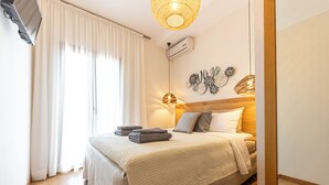 Ein Schlafzimmer mit einem Bett, einem Flachbildfernseher, einer Deckenleuchte und einer Wand-Klimaanlage.