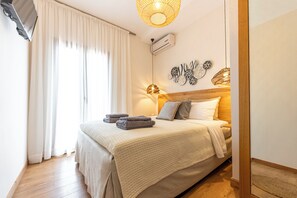 A bedroom with a bed, a flat-screen TV, a ceiling light, and a wall-mounted air conditioner. - 2B Luxurious Villa Io, With Private Pool And Stunningt Sea Views (Skiathos)