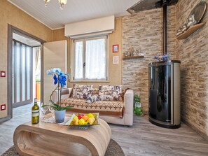 Un salon moderne avec un canapé, une table basse en bois sur laquelle se trouvent des fruits, un réfrigérateur et une fenêtre avec des rideaux.