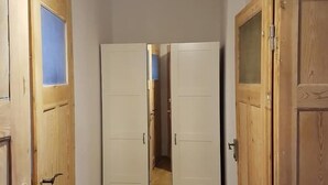 Ein Korridor mit Holztüren, einem Spiegelkleiderschrank und einer Hängeleuchte.