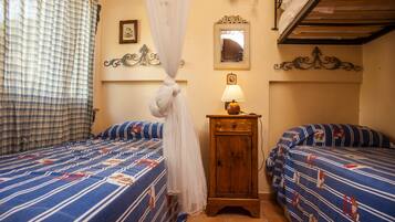 Un dormitorio con dos camas, una mesita de noche con lámpara, un espejo y un ventilador de techo.