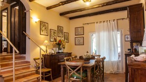 A dining area with a wooden table, chairs, a staircase, and a wooden cabinet. - Villa Stella Close to the Beach with Wi-Fi, A/C, Garden;Parking (Santa Margherita di Pula)