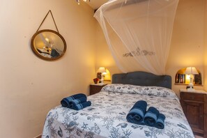 A bedroom with a bed, a bedside table with a lamp, a nightstand, a hanging mirror, and a canopy bed. - Villa Stella Close to the Beach with Wi-Fi, A/C, Garden;Parking (Santa Margherita di Pula)
