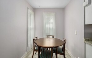 Cozy dining area with a round table and four chairs, surrounded by natural light and a patterned rug.