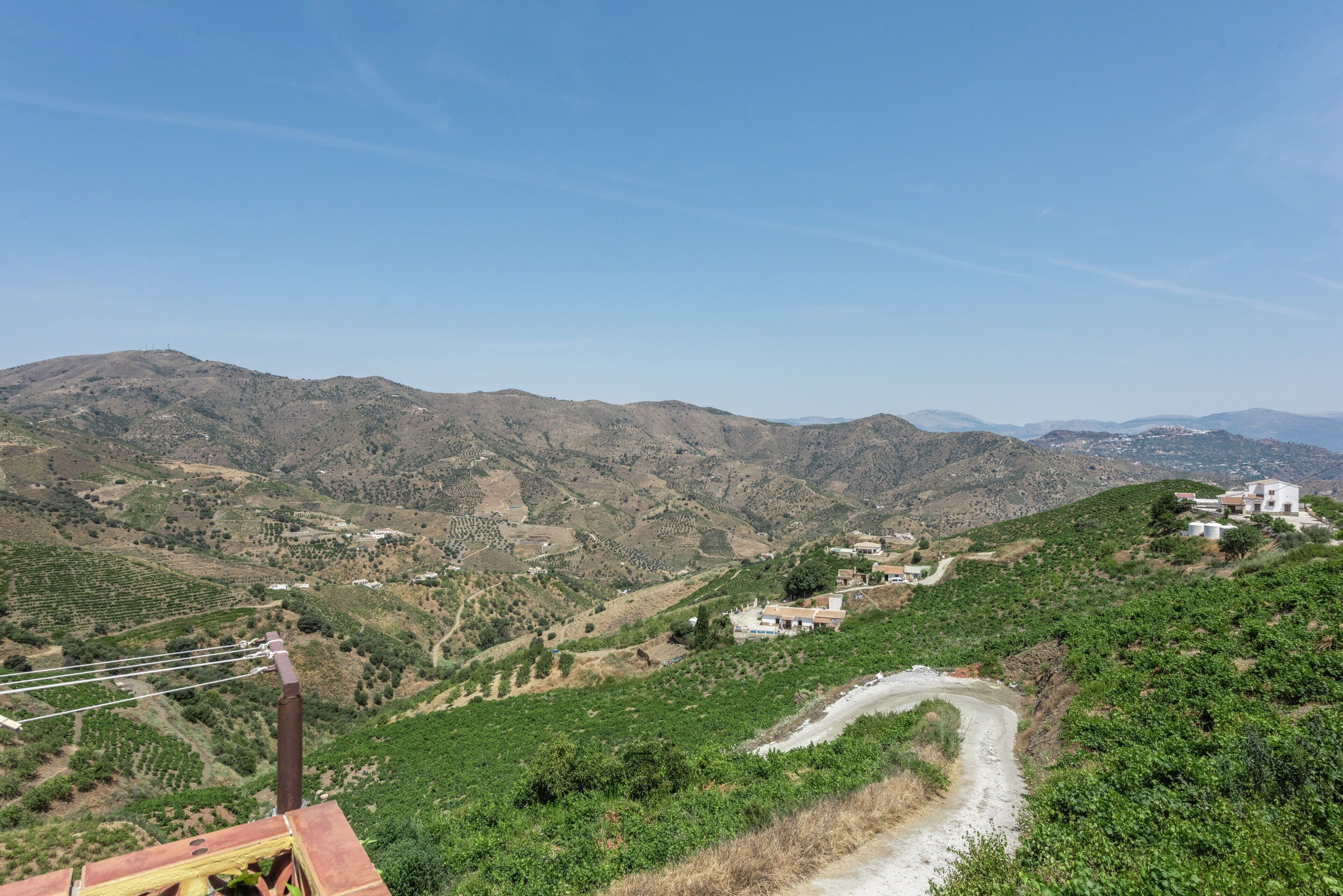 Un paisaje montañoso con una carretera sinuosa, edificios y vegetación.