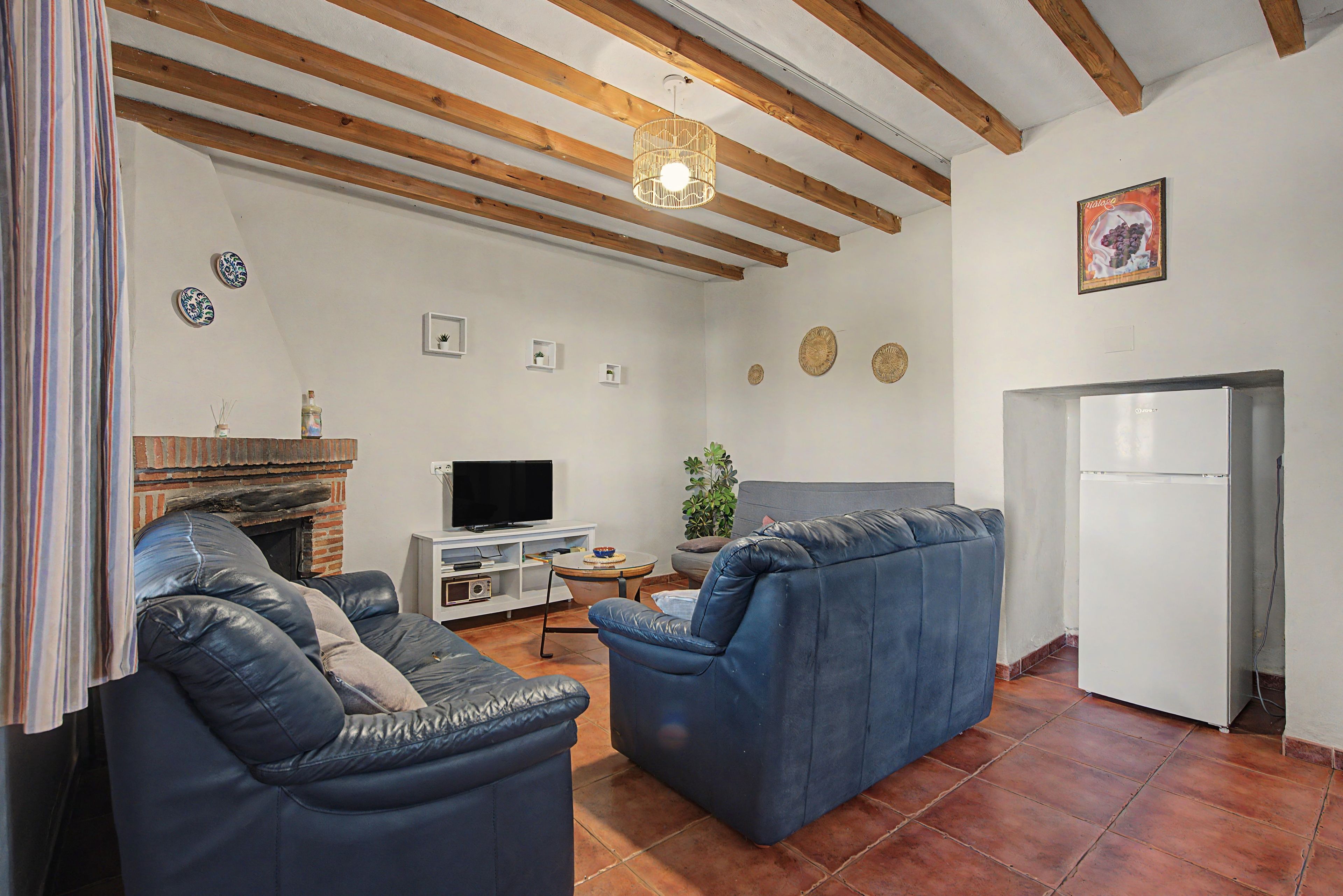 A living room with a fireplace, a television, and a refrigerator.