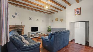 A living room with a fireplace, a television, and a refrigerator.