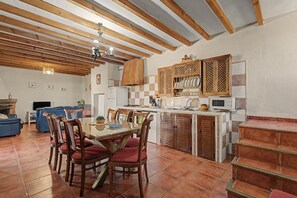 A spacious kitchen with wooden beams, a dining area with red upholstered chairs, and a tiled floor. - House in Peaceful Mountains with Pool, Terrace, Balcony & Wi-Fi; Parking Available (Málaga)