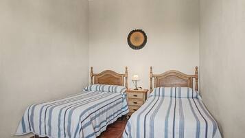 Ein Zimmer mit zwei Einzelbetten, jeweils mit einem Holz-Kopfteil und einem Nachttisch mit einer Lampe.