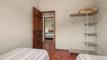Ein Schlafzimmer mit zwei Betten, einem Holzschrank und einem Fliesenboden.
