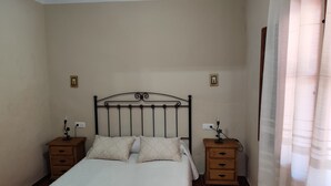 Een slaapkamer met een bed, twee nachtkastjes en een bijzetmeubel met een lamp.