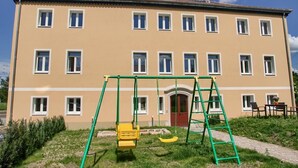 A multi-story building with a playground in front, including swings and a slide. - Dresdner-Tag Helene (Dresden)