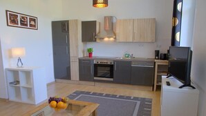 A compact kitchen with modern appliances, a dining area with a glass-top table, and a flat-screen TV. - Dresdner-Tag Helene (Dresden)