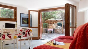 Una habitación con una cama, una mesa con mantel floral, una silla, un televisor y un cuadro en la pared.