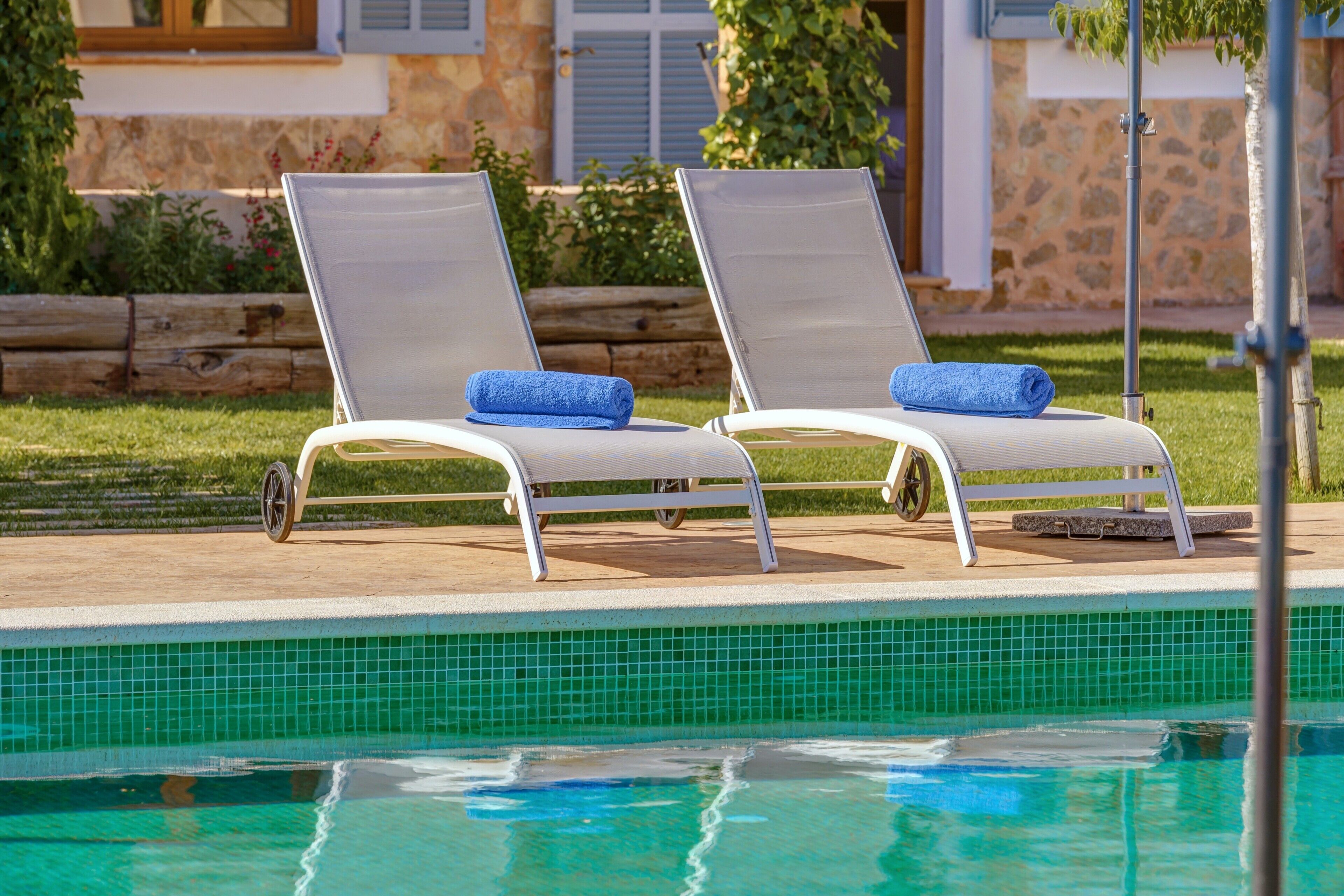 Un espace aménagé au bord de la piscine, avec deux chaises longues et une piscine carrelée.